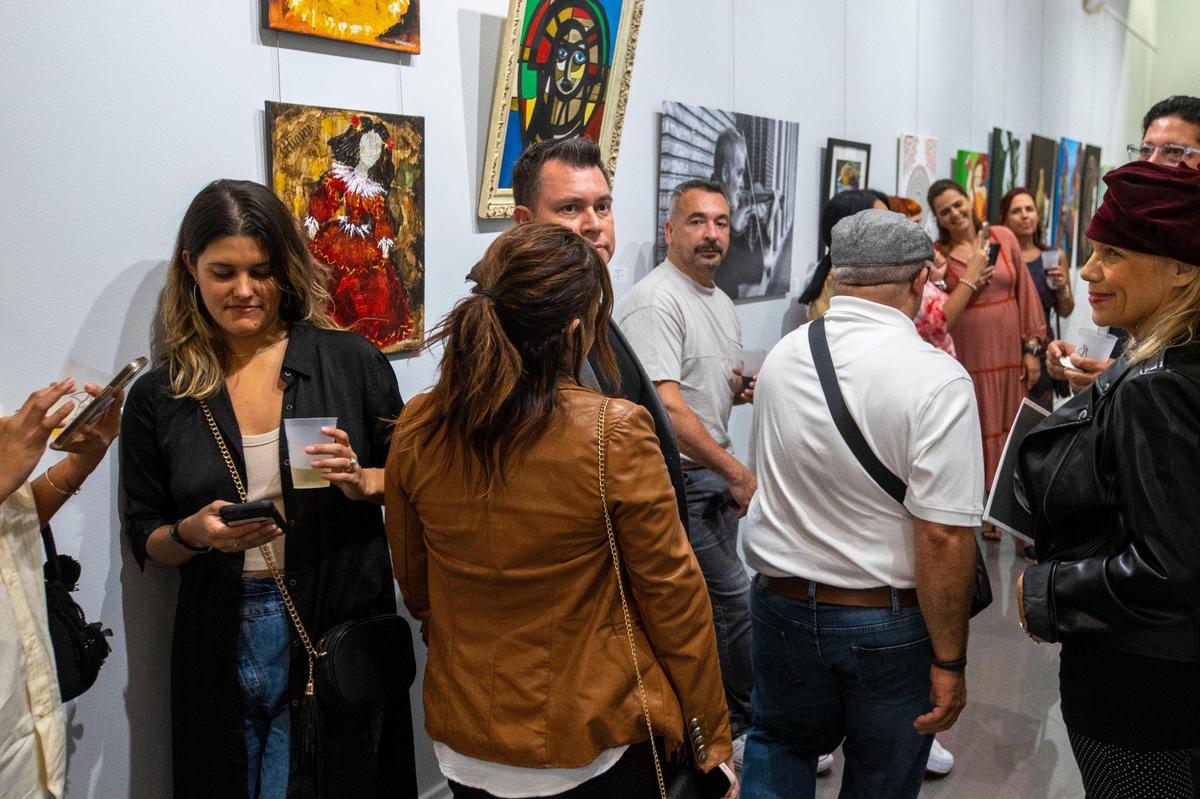 Las personas miran las decenas de obras de arte durante la exposición de artistas latinoamericanos en el Milander Center en Hialeah, Florida, viernes 30 de septiembre de 2022.