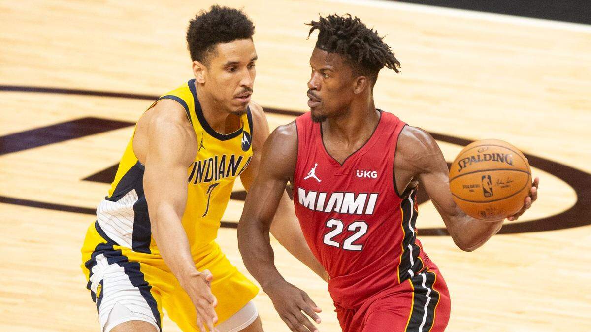 El alero de los Miami Heat Jimmy Butler (22) conduce el balón en el primer cuarto mientras el escolta de los Indiana Pacers Malcolm Brogdon (7) defiende en el AmericanAirlines Arena el viernes 19 de marzo de 2021.