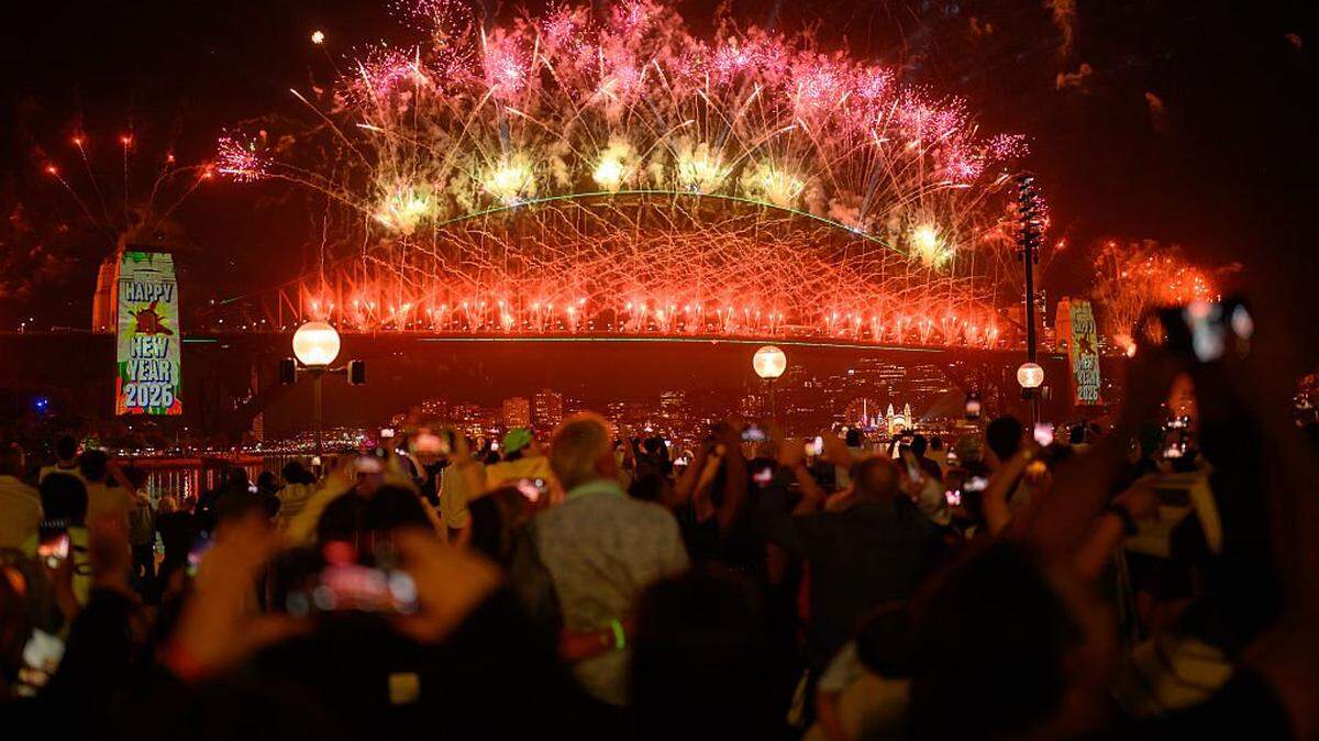 SYDNEY, AUSTRALIA - DECEMBER 31: People enjoy the New Year's Eve firework displays at Opera House on December 31, 2025 in Sydney, Australia. Thousands turned out to celebrate New Year's Eve in Sydney, as the Harbour Bridge lit up with fireworks. (Photo by George Chan/Getty Images)