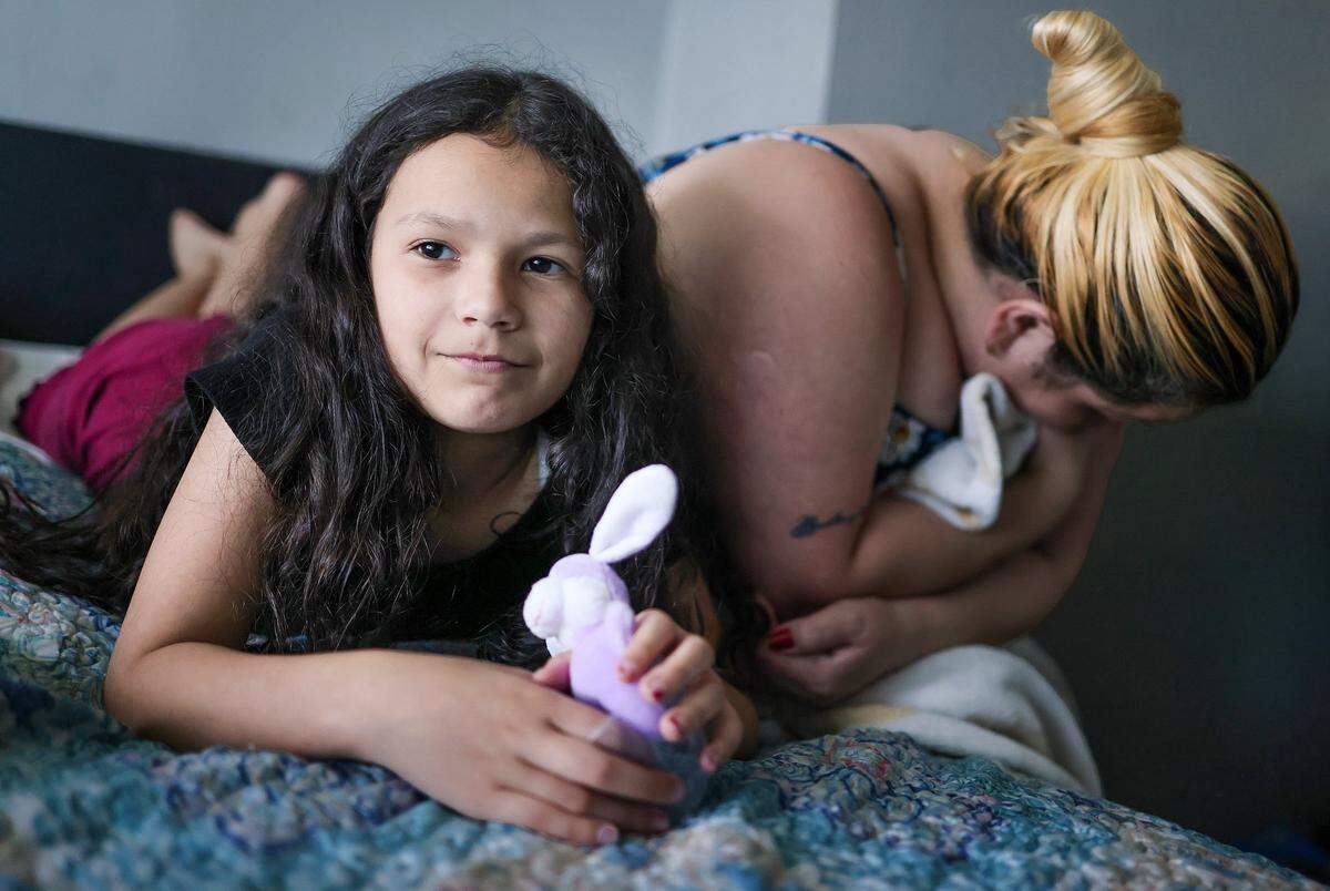 Yelitza Pérez se cubre el rostro junto a su hija Paola, de 9 años en la habitación del motel de Miami donde viven.