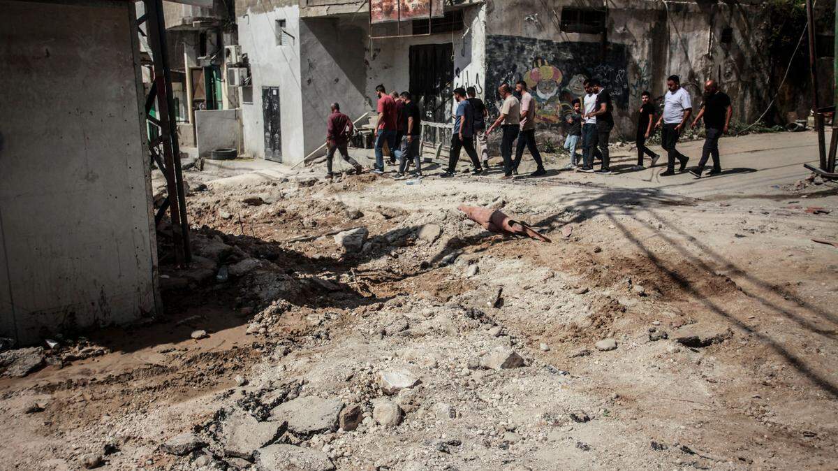 La gente pasa junto a los restos de una operación militar israelí en el campo de refugiados palestinos de Fara, cerca de Tubas, en el norte de Cisjordania ocupada.