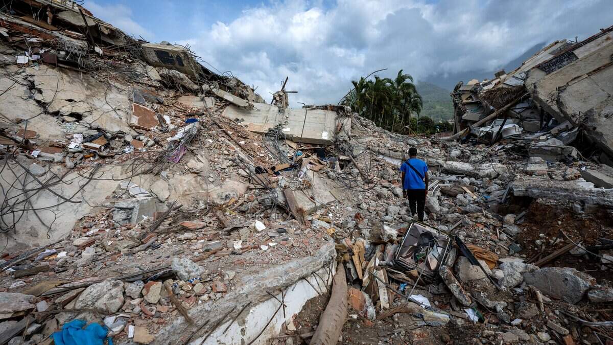 A man walks across the rubble of a collapsed building in Caraballeda, La Guaira state, Venezuela, on July 2, 2026, eight days after twin earthquakes. Hundreds of rescuers in Venezuela cheered and embraced on July 2, 2026 after pulling 43-year-old Hernan Gil from the ruins of a collapsed building eight days after deadly twin earthquakes, AFP journalists witnessed. (Photo by Miguel MEDINA / POOL / AFP via Getty Images)