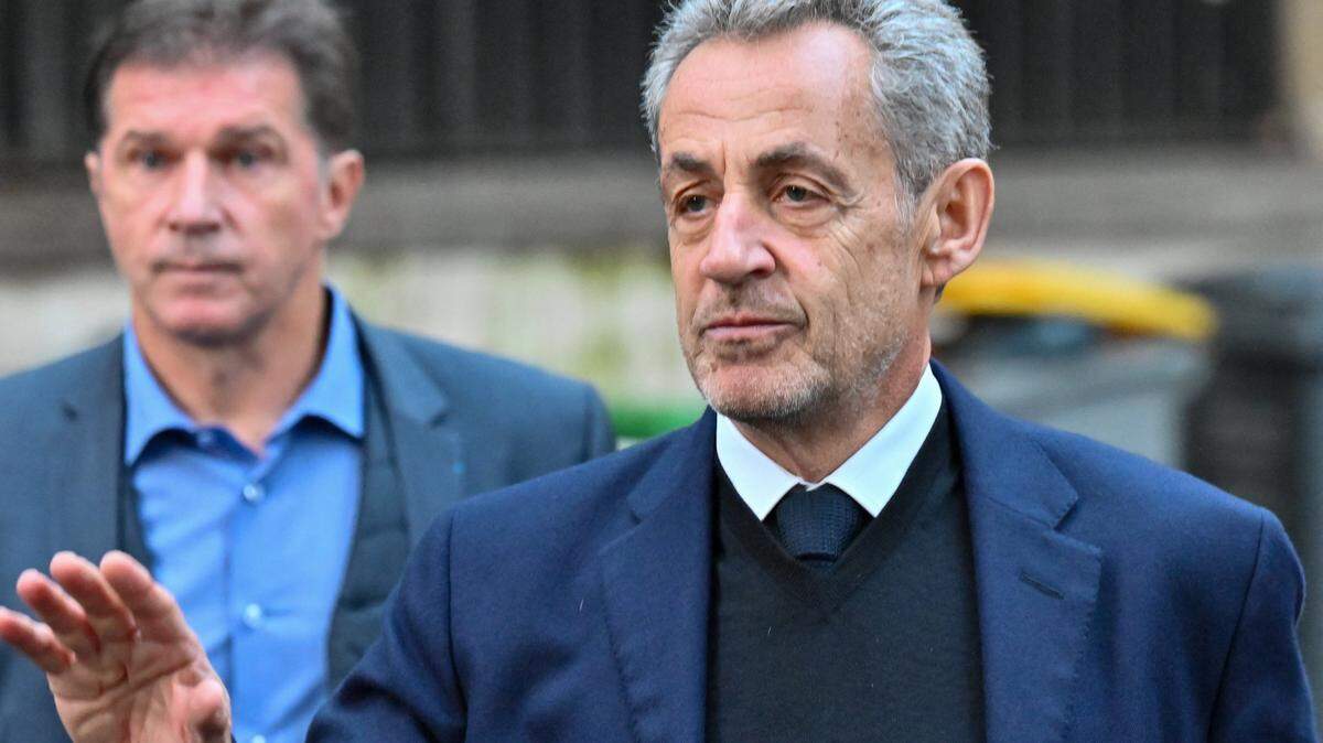Former French President Nicolas Sarkozy, accompanied by his wife Carla Bruni, leaves his home as supporters gather outside to show solidarity on the day he begins serving a five-year prison sentence at La Sante prison. Sarkozy was convicted for criminal association in connection with the alleged illegal financing of his election campaign by Libya, in Paris, France, October 21, 2025. (Photo by Henrique Campos / Hans Lucas via AFP) (Photo by HENRIQUE CAMPOS/Hans Lucas/AFP via Getty Images)