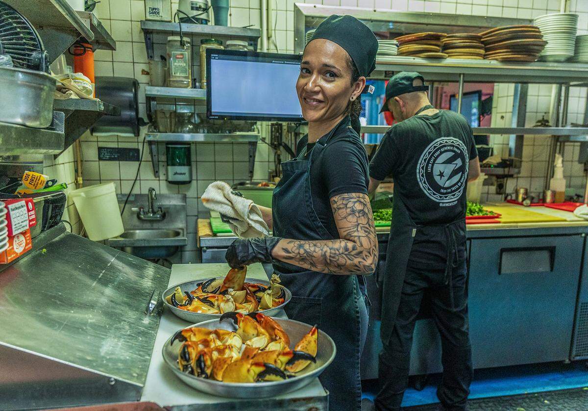 Angela Martínez prepara bandejas de cangrejo de piedra en la cocina del restaurante Catch of the Day en Miami.