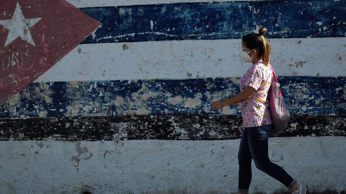 Un cubano con mascarilla pasa junto a un grafiti de la bandera cubana en La Habana, 30 de agosto de 2021. YAMIL LAGE / AFP/ Getty Images