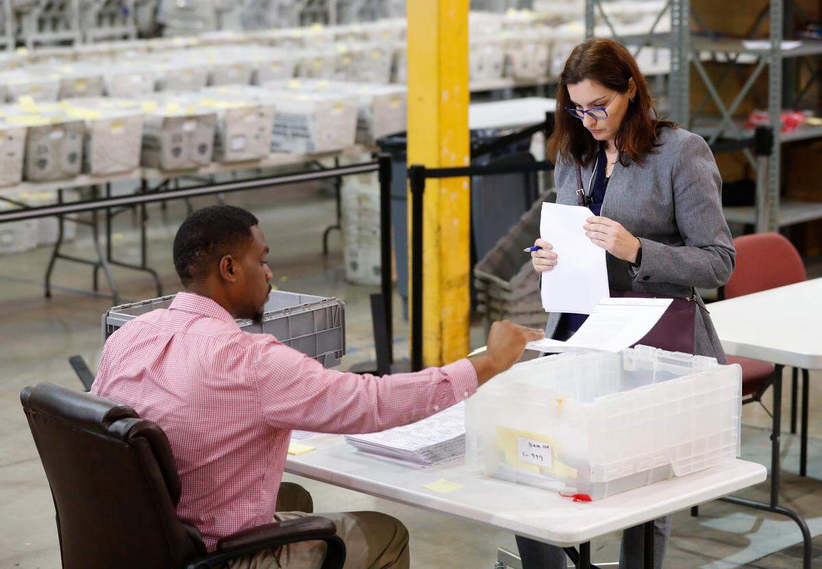 Un observadora republicana observa mientras un empleado electoral del Condado Palm Beach revisa varias boletas dañadas, en una imagen del 15 de noviembre del 2018 en West Palm Beach, Florida.