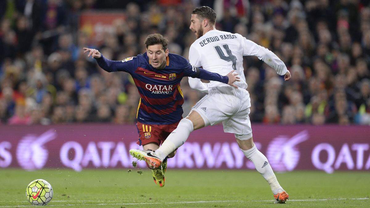Lionel Messi (izq.) es barrido por Sergio Ramos en un partido de la liga española entre Barcelona y Real Madrid, el 2 de abril de 2016.