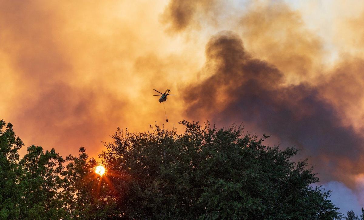 Un helicóptero de Miami-Dade arroja agua sobre un incendio provocado por un incendio de pasto que obligó a la policía a cerrar SW 8th Street en ambas direcciones en SW 137 Avenue debido al denso humo en el área, el domingo 14 de abril de 2024.