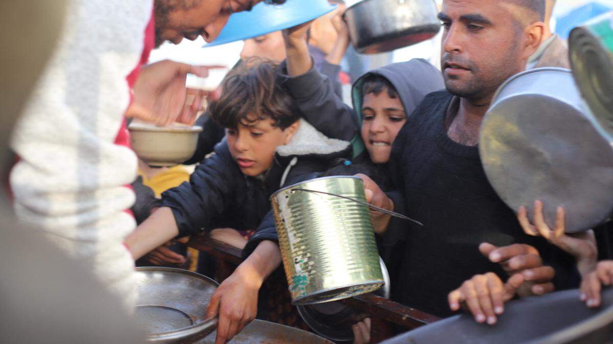 Varios adultos y niños buscan alimentos en un punto de distribución de ayuda humanitaria en Rafah, en el sur de la Franja de Gaza, el domingo 17 de marzo de 2024.