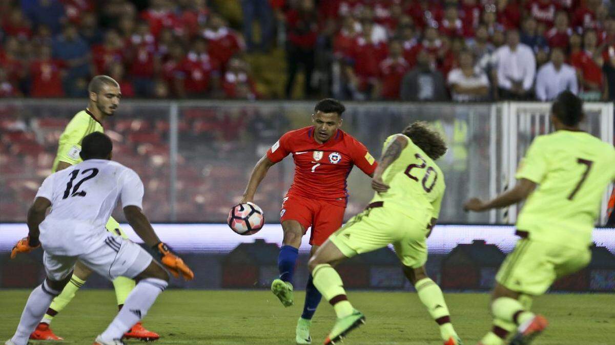 El delantero de Chile Alexis Sánchez (centro) patea el balón ante la defensa de Venezuela, en el partido efectuado el 28 de marzo del 2017 en Santiago.