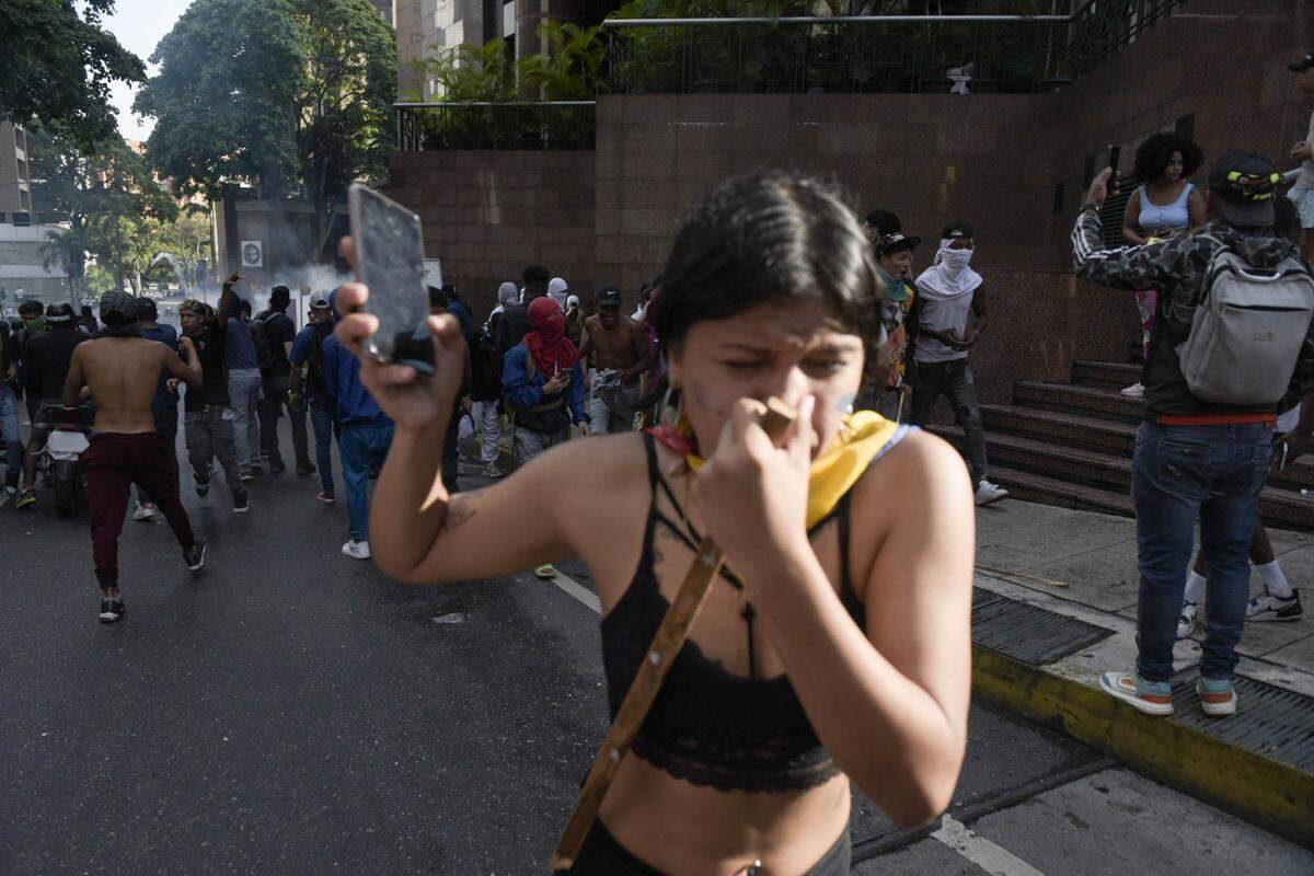Una mujer huye de los gases lacrimógenos lanzados por agentes de la Guardia Nacional para reprimir una protesta en contra de los resultados de las elecciones presidenciales en Venezuela, el lunes 29 de julio de 2024, en el vecindario de Petare de Caracas. 