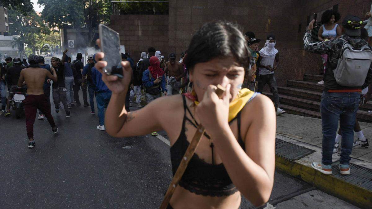 Una mujer huye de los gases lacrimógenos lanzados por agentes de la Guardia Nacional para reprimir una protesta en contra de los resultados de las elecciones presidenciales en Venezuela, el lunes 29 de julio de 2024, en el vecindario de Petare de Caracas.
