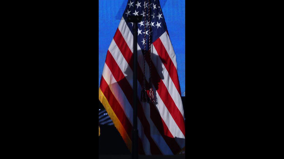 La sombra del presidente Donald Trump se proyecta sobre la bandera mientras sube al escenario para dirigirse a los asistentes del Foro Empresarial Estadounidense en el Centro Kaseya de Miami el pasado 5 de noviembre.