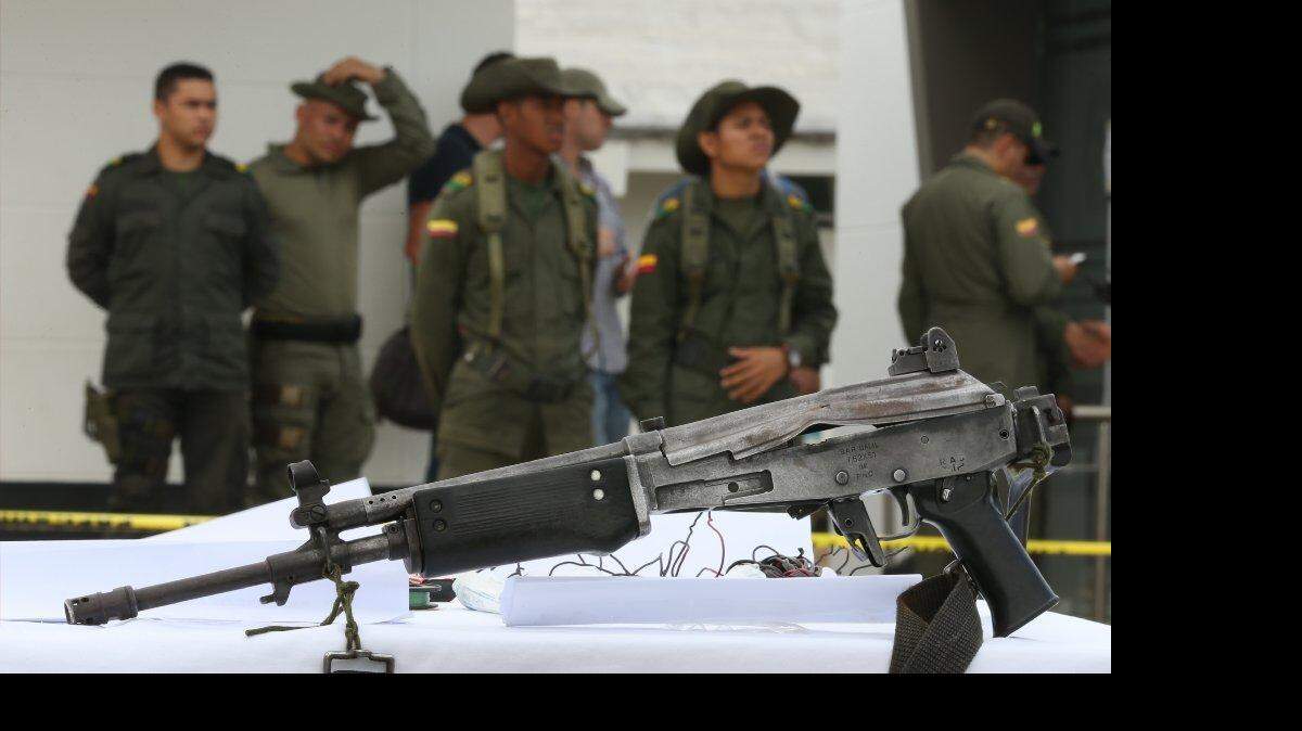 Oficiales de policía se paran detrás de un arma incautada en la estación de policía en Necoclí, Colombia, el miércoles, 11 de marzo de 2015. El general Ricardo Restrepo el comandante de policía antinarcóticos dijo que la munición, armas y cerca de 170 kilogramos de cocaína perteneciente a la banda criminal "Los Usuga" fueron capturados el martes en la localidad rural de Necoclí, en el departamento de Antioquia.