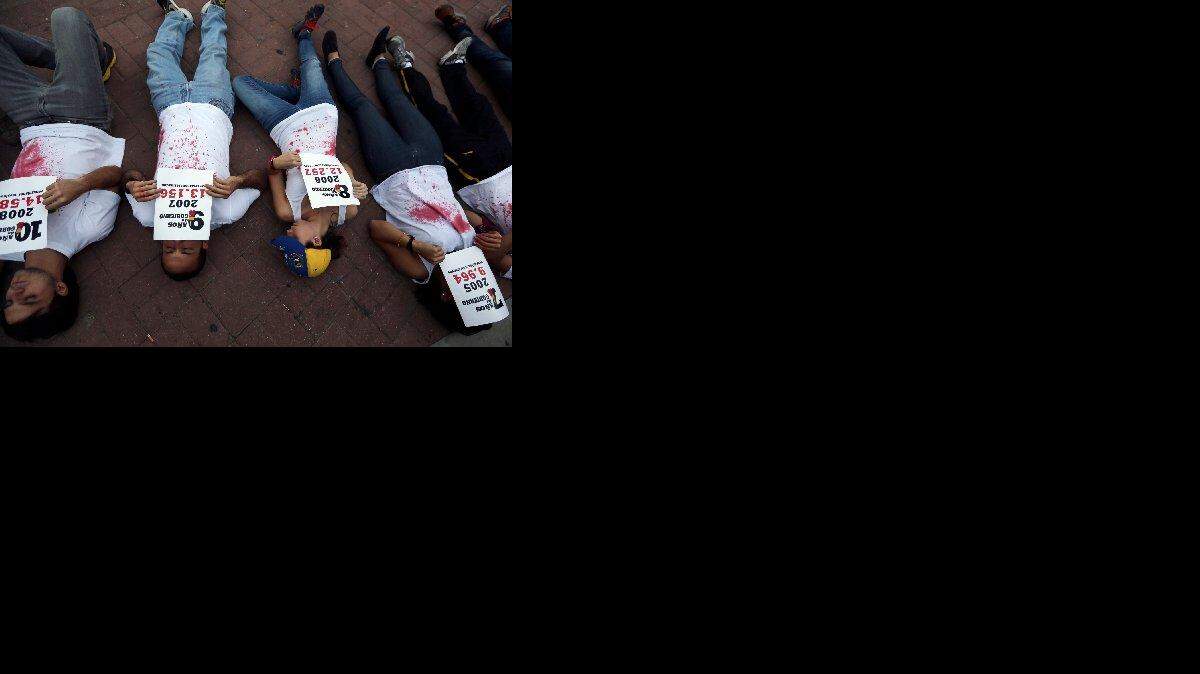 Manifestantes venezolano acostados en el piso muestran pancartas con las estadísticas de personas asesinadas durante los 14 años del gobierno chavista, durante una protesta en Caracas en el 2014.
