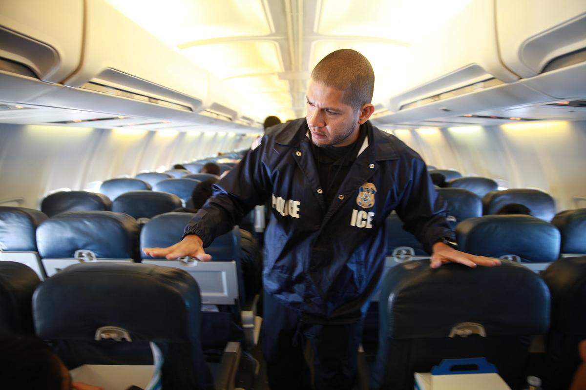 Un funcionario de ICE ERO supervisa un vuelo con migrantes deportados.