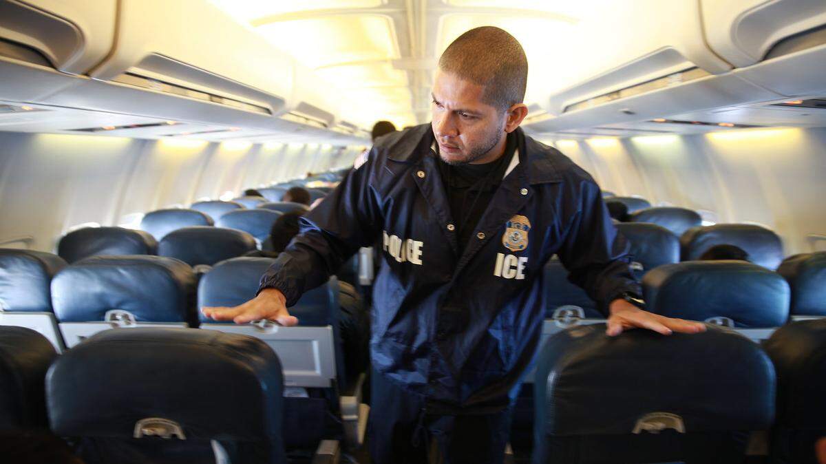 Un funcionario de ICE ERO supervisa un vuelo con migrantes deportados, imagen que refleja el endurecimiento de las medidas migratorias, incluidos los avisos de USCIS sobre expulsiones por estadías vencidas.