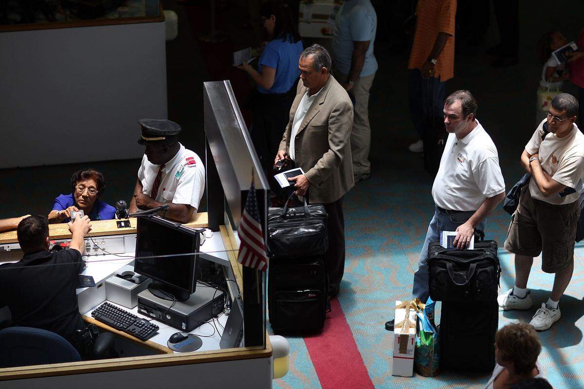 MIAMI - JUNE 22: A Customs and Border Protection officer checks passports at the passport control booth as people enter the United States through the Miami International Airport June 22, 2007 in Miami, Florida. The Bush administration on Wednesday postponed for at least six months a requirement that Americans returning by land or sea from Canada, Mexico and Caribbean nations must carry passports.The rule, due to go into effect in January 2008, will be delayed until the summer of that year. (Photo by Joe Raedle/Getty Images)