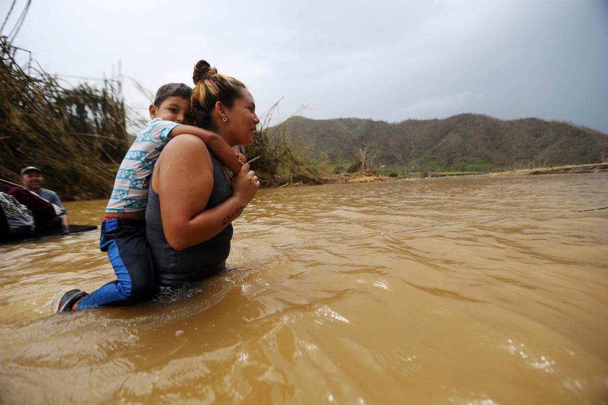Marlene Ojeda carga a su hijo para cruzar el río San Lorenzo de Morovis tras el huracán María, el 27 de septiembre del 2017.