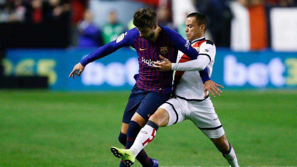 El defensa de Barcelona Gerard Piqué (izq.) lucha por la pelota con Raúl de Tomás, del Rayo Vallecano, en el partido celebrado el 3 de noviembre de 2018 en Madrid.