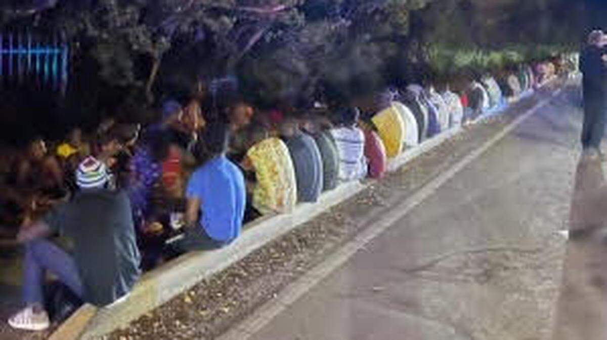 Un grupo de migrantes haitianos sentados en la carretera en Cayo Hueso, Florida, el miércoles 26 de junio de 2024 por la mañana.