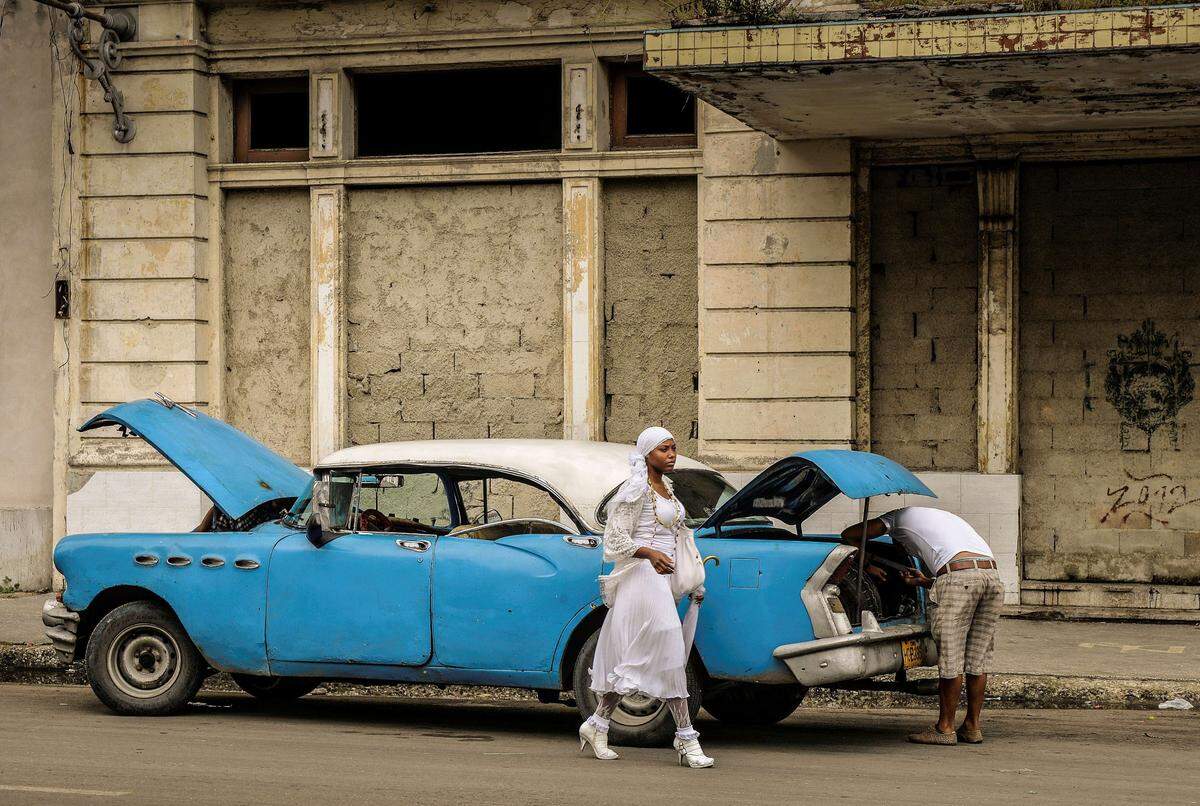 Una mujer camina junto a un viejo auto norteamericano en La Habana. Archivo.