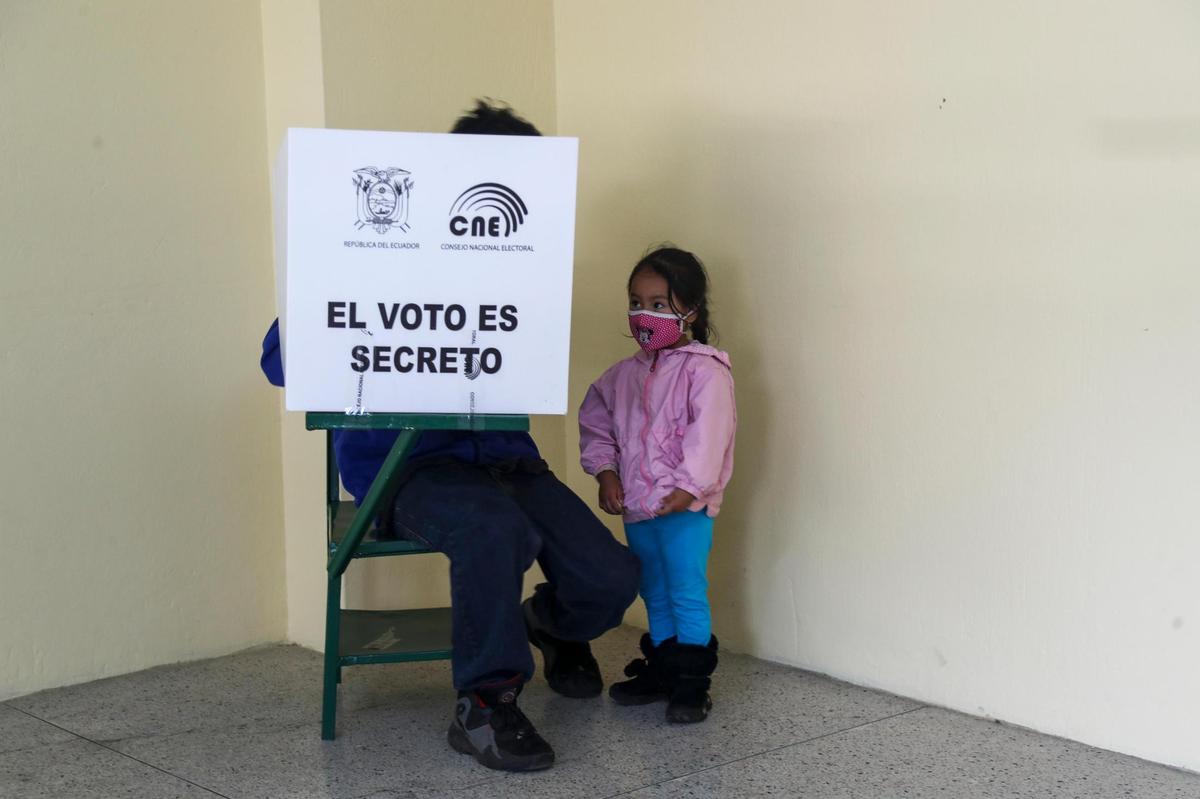 Un votante, acompaÃ±ado de su hija, marca su boleta durante la segunda vuelta de las elecciones presidenciales en Quito, Ecuador, el domingo 11 de abril de 2021. Los ecuatorianos estÃ(degrees)n votando, en medio de la pandemia de COVID-19, para elegir entre AndrÃ©s Arauz, de la coaliciÃ³n UniÃ³n de la Esperanza y un economista protegido del expresidente Rafael Correa, y el exbanquero Guillermo Lasso, del partido Creando Oportunidades o CREO. (Foto AP/Dolores Ochoa)