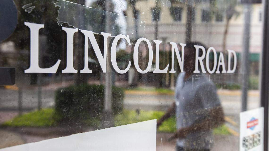 Un hombre caminando por el Lincoln Road Mall de Miami Beach se refleja en el escaparate de una tienda vacía.
