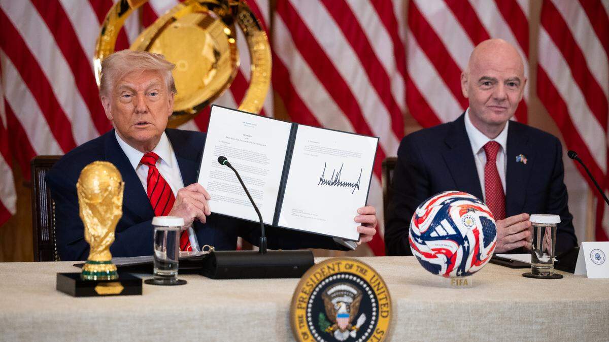 El presidente Donald Trump sostiene la carta constitutiva del Grupo de Trabajo de la Casa Blanca para la Copa Mundial de la FIFA 2026, mientras el presidente de la FIFA, Gianni Infantino, observa durante una reunión del grupo en la Sala Este de la Casa Blanca, el martes, 6 de mayo de 2025.