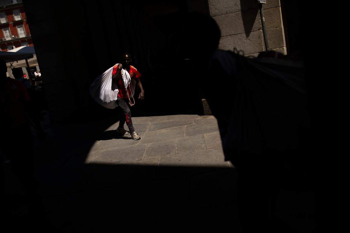 Un “mantero” carga sus mercancias mientras camina por la arcada de la Plaza Mayor, en el centro de Madrid, el 24 de julio del 2018