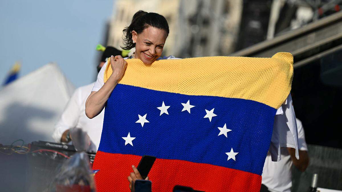 La líder opositora venezolana María Corina Machado sostiene una bandera de Venezuela mientras simpatizantes se reúnen en la Puerta del Sol de Madrid el 18 de abril de 2026.