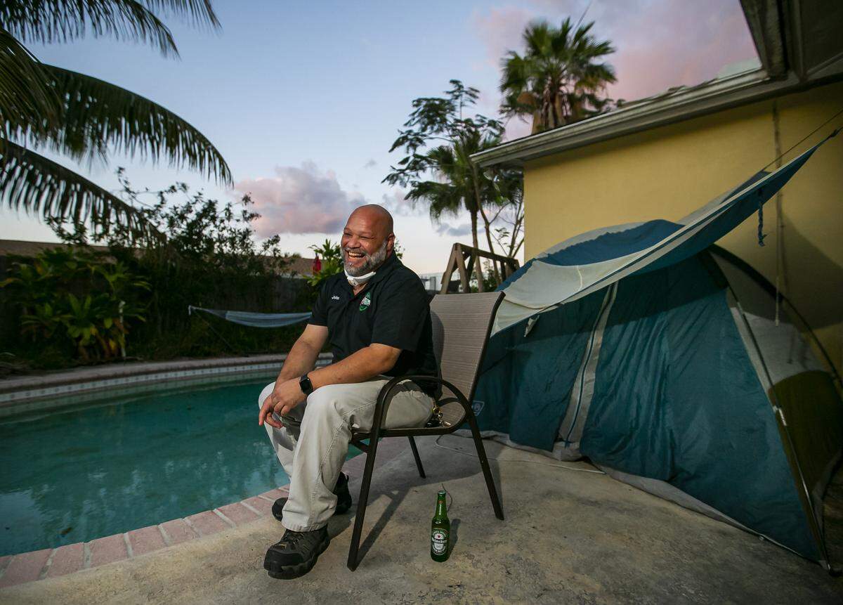 John Delgado, de 52 años, bebe una cerveza mientras espera el anochecer en su casa en Homestead el miércoles 1 de abril de 2020. Delgado, que trabaja con el público en un banco de alimentos, optó por quedarse en una tienda de campaña en su patio trasero para evitar cualquier posibilidad de exponer a los miembros de la familia al coronavirus.
