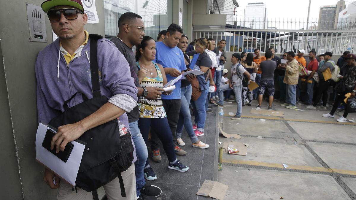Ciudadanos venezolanos hacen fila afuera de la oficina del Ministerio del Exterior en Lima, el 23 de enero de 2018.