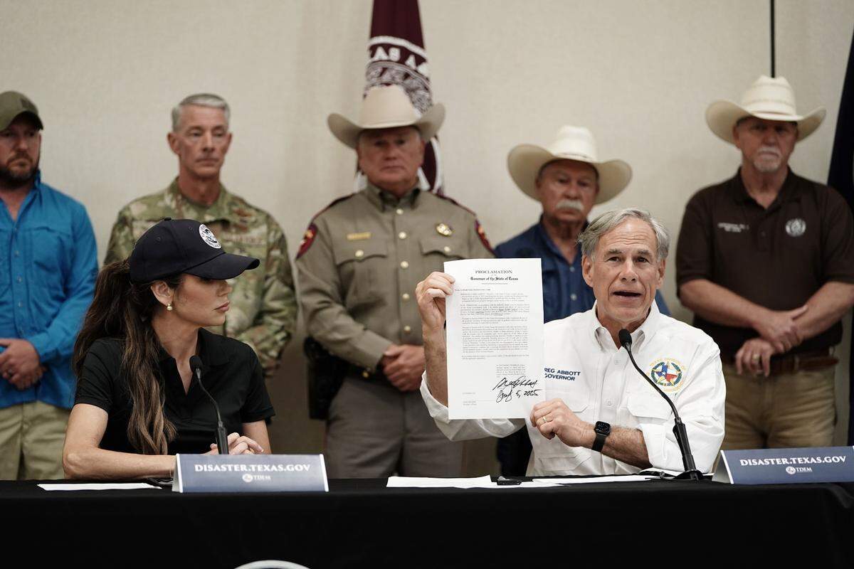El gobernador de Texas, Greg Abbott (der.), firma una declaración de desastre acompañado de la secretaria de Seguridad Nacional, Kristi Noem (izq.), en Kerrville, Texas, EE. UU., el 5 de julio de 2025.