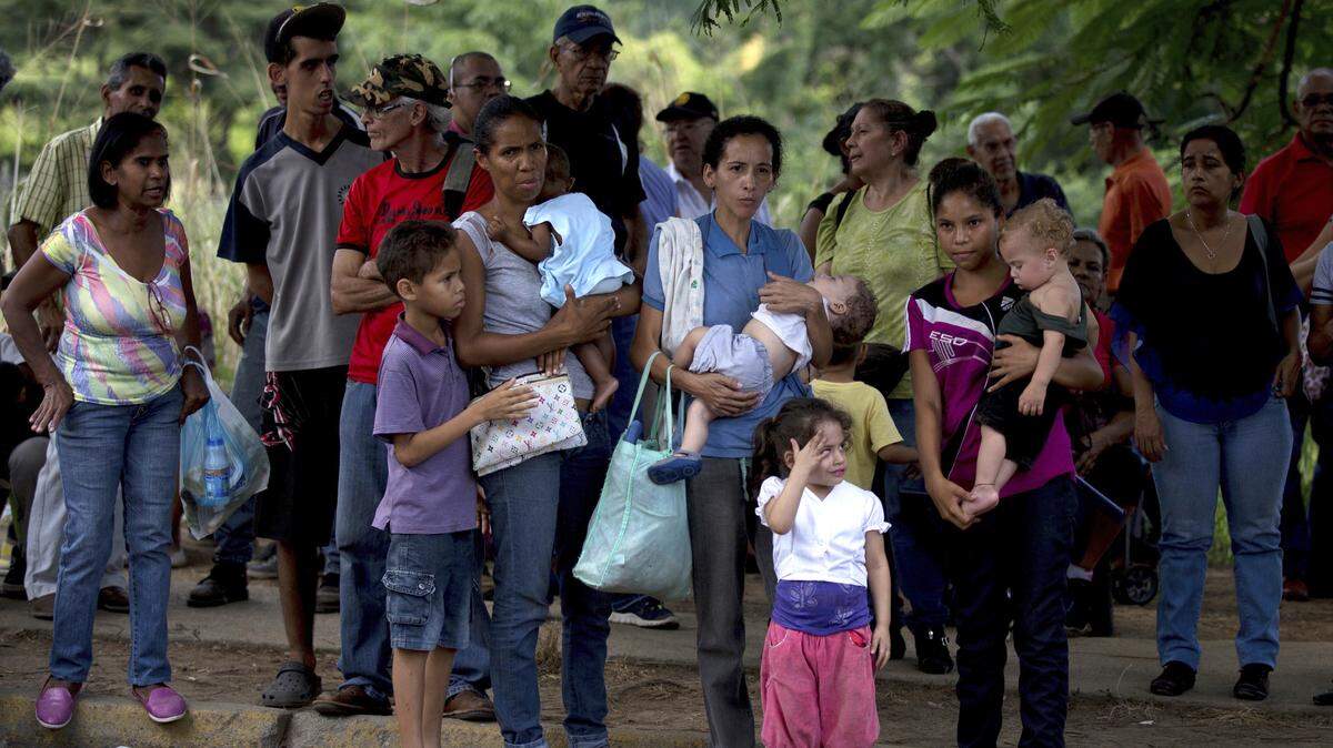 En esta foto del 18 de octubre de 2017, una mujer acuna a su hija mientras espera en fila para comprar comida en un supermercado, en Guarenas, en el estado venezolano de Miranda.