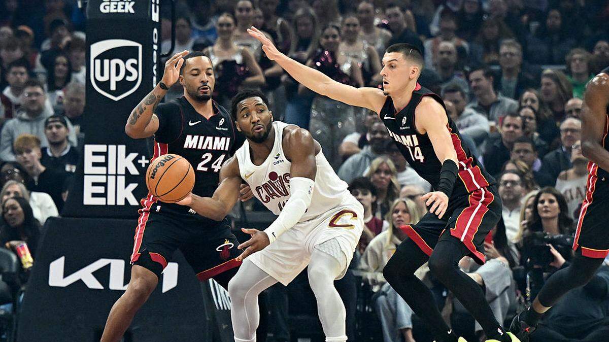 El astro de los Cavaliers Donovan Mitchell trata de pasar la pelota ante la maca de Norman Powell (izq.) y Tyler Herro, en el partido de la NBA celebrado el 25 de marzo de 2026 en Cleveland. 