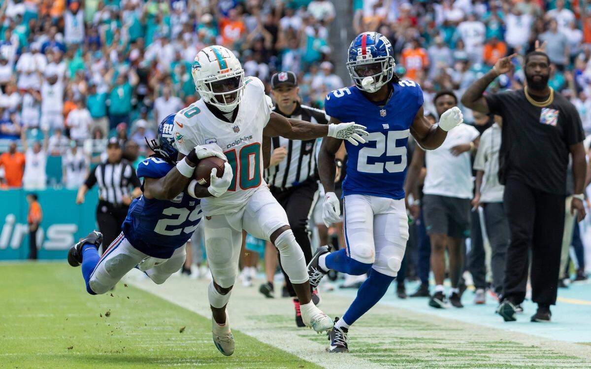 El wide receiver de los Dolphins Tyreek Hill (centro) corre con el ovoide ante la defensa de los Giants de Nueva York, en el partido de la NFL celebrado el 8 de octubre de 2023 en el Hard Rock Stadium en Miami Gardens, Florida.