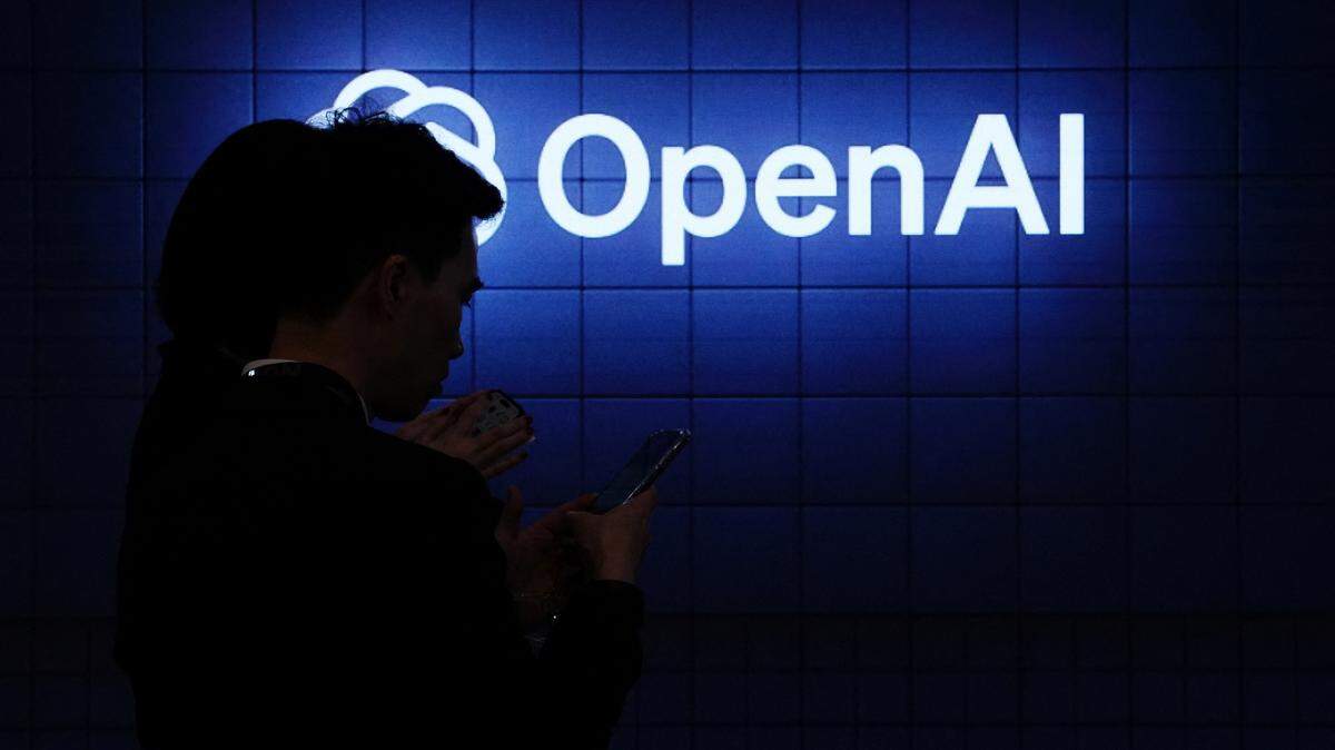 Visitor look at their phone next to an Open AI's logo during the Mobile World Congress (MWC), the telecom industry's biggest annual gathering, in Barcelona on February 26, 2024. The world's biggest mobile phone fair throws open its doors in Barcelona with the sector looking to artificial intelligence to try and reverse declining sales. (Photo by PAU BARRENA / AFP) (Photo by PAU BARRENA/AFP via Getty Images)