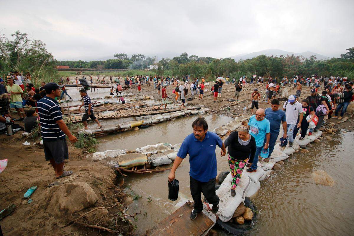 La gente cruza el río Táchira hacia Colombia, cerca del puente internacional Simón Bolívar, que las autoridades venezolanas solo abren a estudiantes y enfermos, en Cucuta, Colombia, el martes 12 de marzo de 2019, en la frontera con Venezuela. Las personas que cruzan el río están utilizando puentes improvisados a medida que el nivel del agua crece a medida que se acerca la temporada de lluvias.