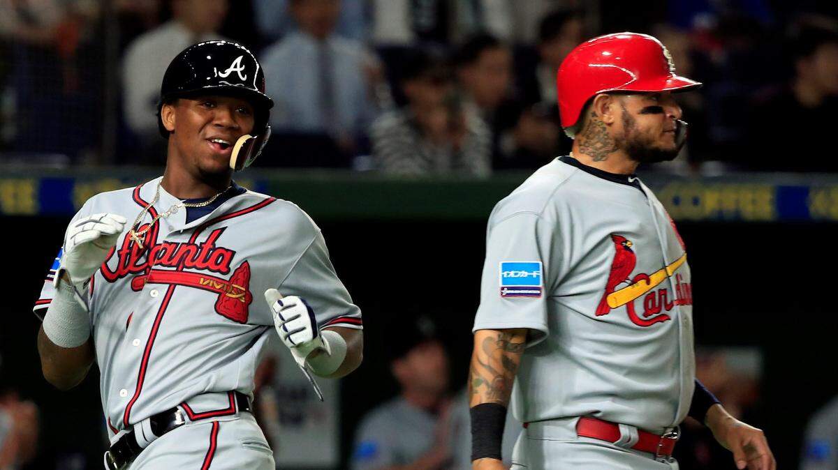 El jardinero venezolano de los Bravos Ronald Acuña Jr. (izq.) y el receptor puertorriqueño de los Cardenales Yadier Molina durante una jugada en la primera entrada del partido disputado entre el equipo de estrellas de Grandes Ligas y los Gigantes de Yomiuri, el jueves 8 de noviembre de 2018 en el estadio Tokio Dome, en Tokio, Japón.