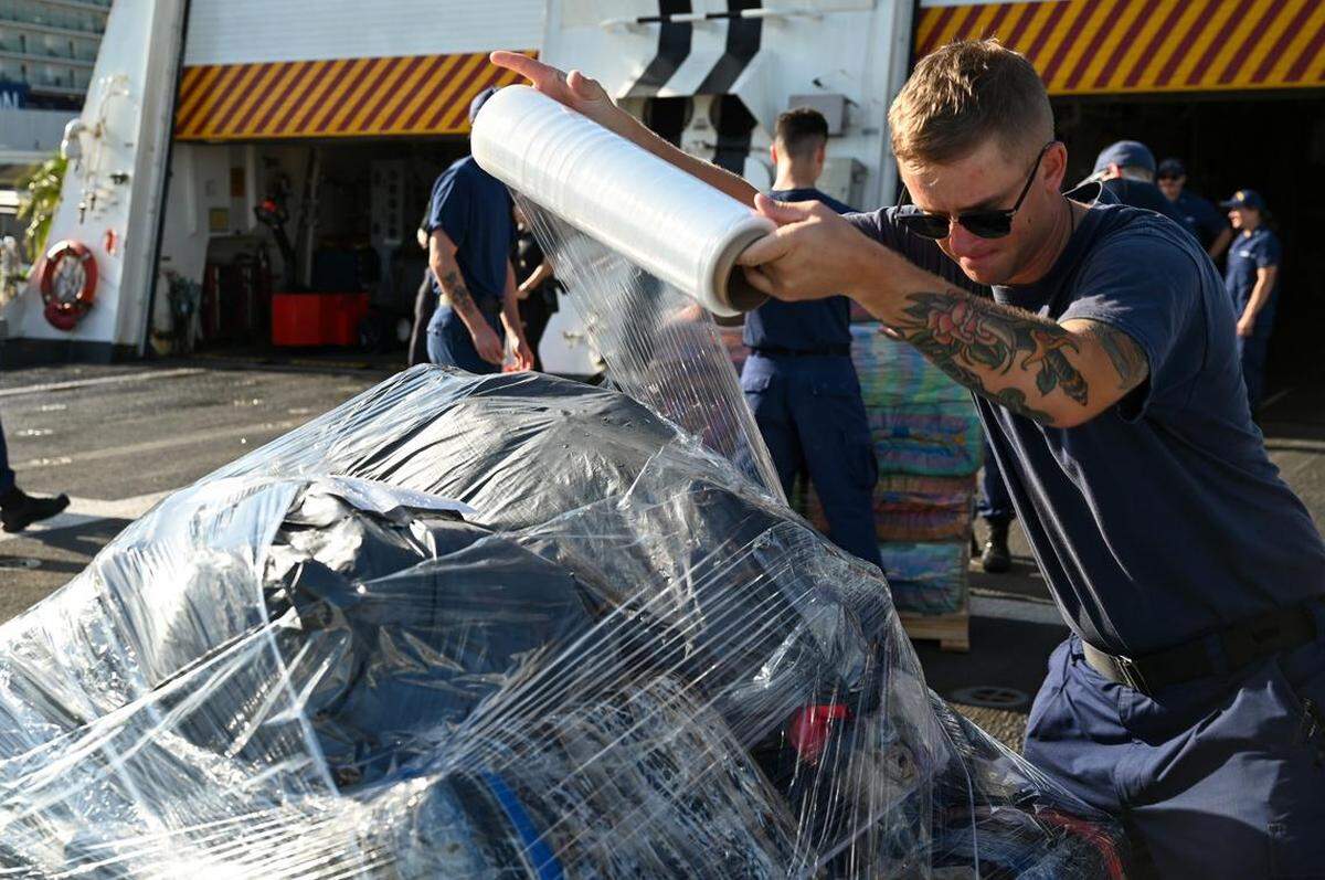 Un tripulante del escampavías Hamilton, del Servicio Guardacostas, envuelve drogas en plástico durante una descarga de aproximadamente 34,800 kg de narcóticos ilegales en Port Everglades, el lunes 25 de agosto de 2025.