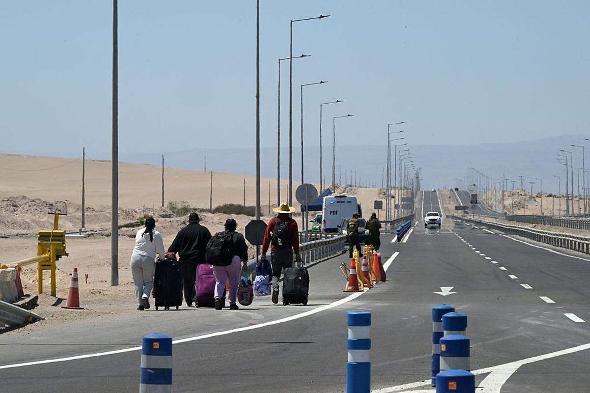 Migrants walk back to Chile after they were not allowed to enter Peru, near de Cachalluta border crossing, about 25 km north of Arica, Chile, on November 30, 2025. Dozens of migrants seeking to leave Chile were stranded at the border with Peru, authorities said on Friday, amid fears sparked by far-right Chilean presidential candidate Jose Antonio Kast's threat to expel undocumented migrants. (Photo by Rodrigo ARANGUA / AFP via Getty Images)