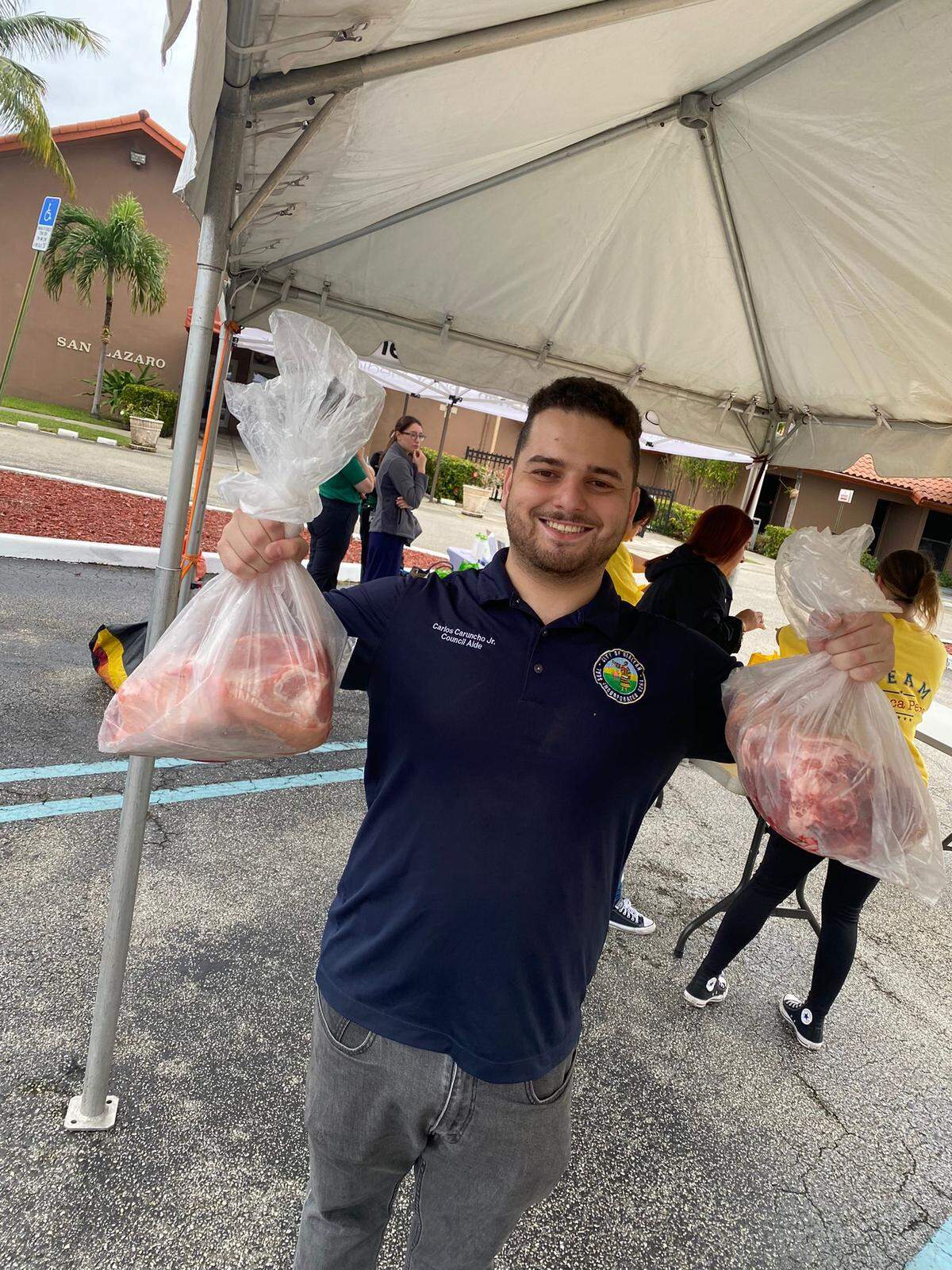 Carlos Caruncho, Jr, asistente de la presidenta del concejo, Mónica Pérez, reparte paletas de cerdo en la iglesia San Lázaro, en Hialeah