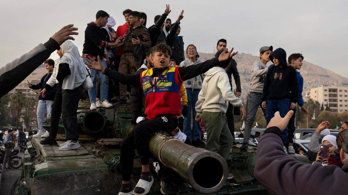 Una decena de personas se sube a un tanque para celebrar la caída del régimen de Bashar al Asad en Damasco, Siria, el martes 10 de diciembre de 2024.