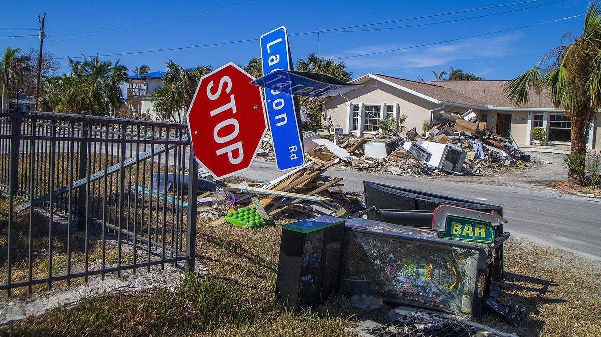 Una señal de alto derribada descansa sobre una cerca en la esquina de las carreteras Lagoon y Tarpon en Fort Myers Beach, junto a artículos como una máquina de pinball y electrodomésticos, el miércoles 26 de octubre de 2022. 