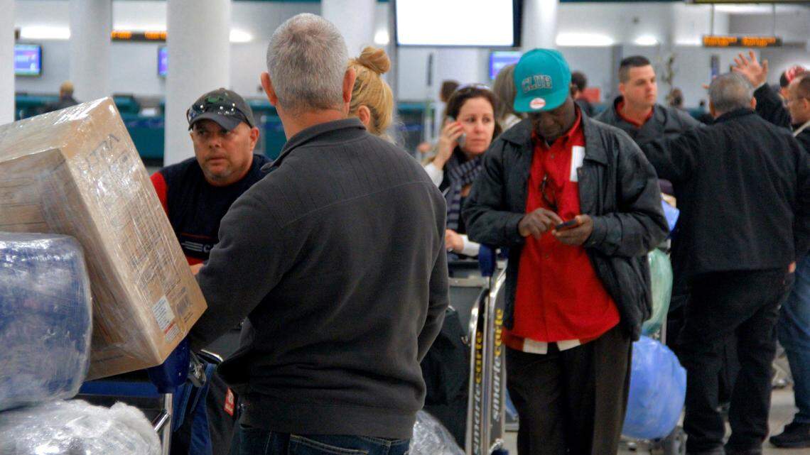 People wait in line, with luggage wrapped in plastic, for a Havana Air charter flight to Cuba.