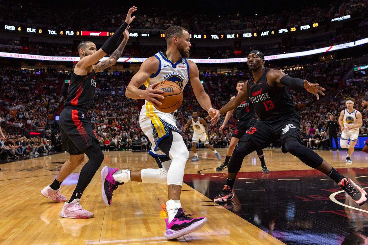 El jugador de los Warriors de Golden State Stephen Curry trata de entrar al aro ante la marca Caleb Martin (16) y Bam Adebayo (13), del Heat, en el partido celebrado el 26 de marzo de 2024 en Miami.