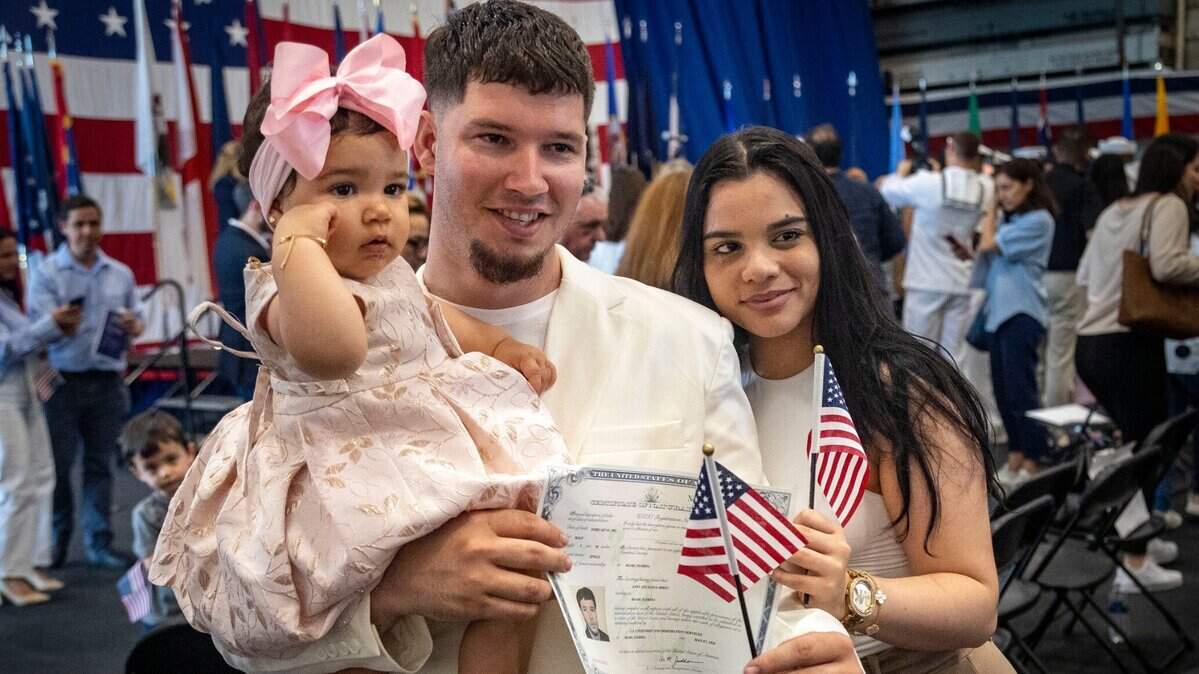 Andy Escalona Abreu, recién juramentado como ciudadano estadounidense, originario de Cuba, posa para fotos con su hija Leah Escalona de 10 meses y su esposa Talia López después de la ceremonia de naturalización a bordo del USS Battan en Miami.