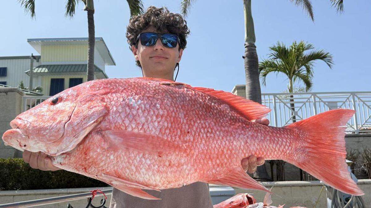 El pescador Tony Figlozzi, de Iowa, posa con un gran pargo rojo de 34 pulgadas, que capturó con el capitán Brian Lambert.