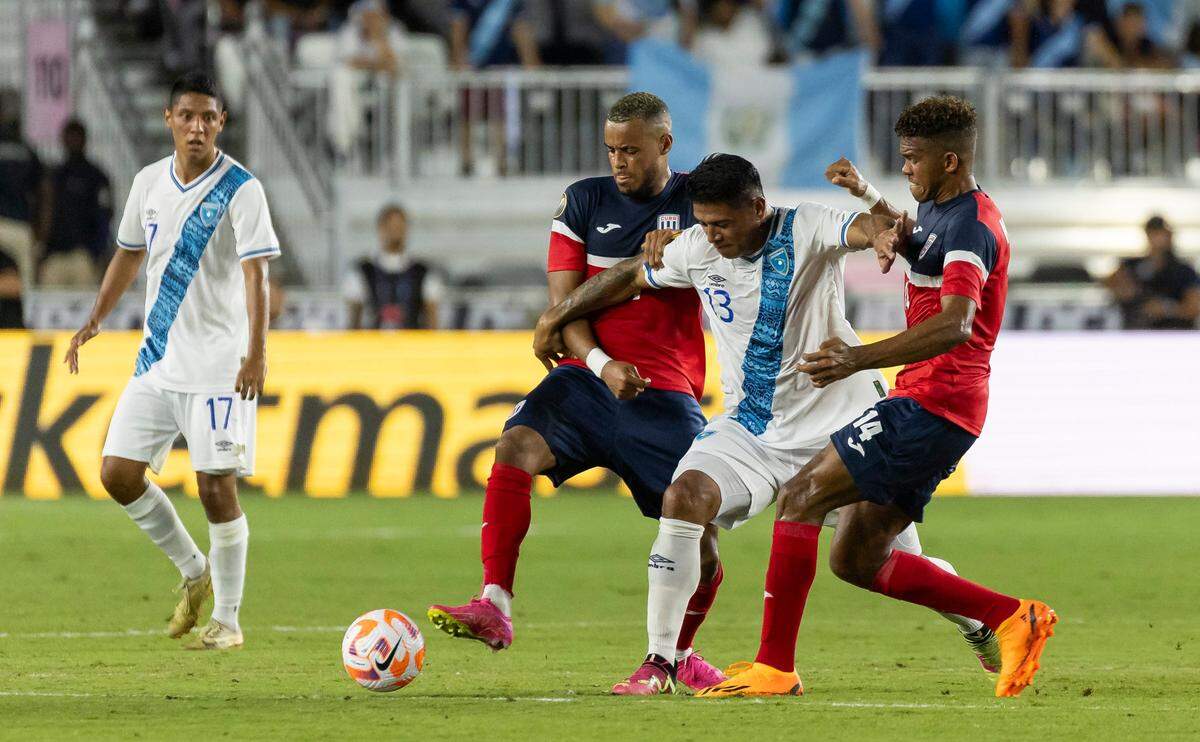 El jugador de Guatemala Alejandro Galindo (centro) trata de pasar la marca de los cubanos Neisser Sandó (der.) y Modesto Méndez, en el partido de la Copa Oro celebrado el 27 de junio de 2023 en el DRV PNK Stadium de Fort Lauderdale, Florida.